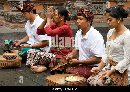 Mehrere Menschen beten und Angebote in den Heiligen Affenwald anlässlich des Galungan zu verlassen. Galungan Festival, das wichtigste von Bali, symbolisiert den Sieg des Dramas (Tugend) über Adharma (böse). Während der Tage, die balinesischen Parade feiern auf der ganzen Insel geschmückt mit langen Bambusstäben (Penjor) dekoriert mit Ähren, Kokosnuss, Reiskuchen und Muffins sowie weiße oder gelbe Stoffe dauern, Früchte Blumen. Dieses Festival wird alle 210 Tage gefeiert. Ubud. Bali. Stockfoto