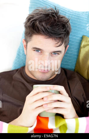 Kranker Mann liegend auf dem Sofa mit einer Tasse Stockfoto