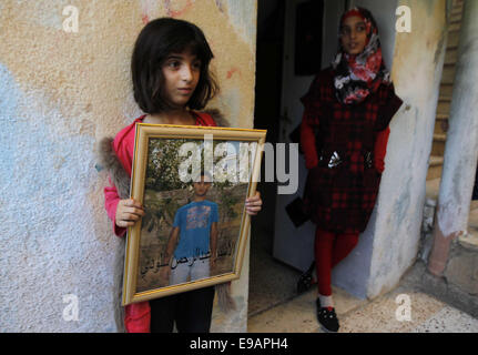 Jerusalem, Palästina. 23. Oktober 2014. Die Schwester eines palästinensischen Mannes Abdelrahman Shaludi, wer hat ein Baby getötet und sechs weitere in Jerusalem, nachdem er sein Fahrzeug Fußgänger in der Nähe von einer Straßenbahn in welche israelische Polizei genannt '' Fahrerflucht Terrorangriff rammte '' verletzt, schaut zu, wie ihre Schwester sein Porträt auf ihre Familie zu Hause in der Ost-Jerusalem-Nachbarschaft von Silwan am 23. Oktober 2014 hält. Shaludi starb an seinen Verletzungen, nachdem er erschossen wurde und von der Polizei verletzt, als er versuchte, die Szene zu spät am Abend zuvor Credit fliehen: Muammar Awad/APA Bilder/ZUMA Draht/Alamy Live News Stockfoto