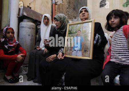 Jerusalem, Palästina. 23. Oktober 2014. Die Mutter und andere Familienmitglieder eines palästinensischen Mannes Abdelrahman Shaludi, wer hat ein Baby getötet und sechs weitere in Jerusalem, nachdem er sein Fahrzeug Fußgänger in der Nähe von einer Straßenbahn in welche israelische Polizei genannt '' Fahrerflucht Terrorangriff rammte '' verletzt, festhalten, sein Porträt auf ihre Familie zu Hause in der Ost-Jerusalem-Nachbarschaft von Silwan 23. Oktober 2014. Shaludi starb an seinen Verletzungen, nachdem er erschossen wurde und von der Polizei verletzt, als er versuchte, die Szene zu spät am Abend zuvor Credit fliehen: Muammar Awad/APA Bilder/ZUMA Draht/Alamy Live News Stockfoto