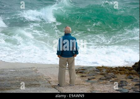 Ein senior woman Blick auf eine aufgewühlte Meer St Ives Cornwall England uk Stockfoto