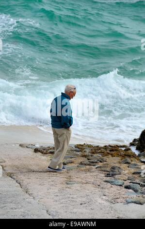 Ein senior woman Blick auf eine aufgewühlte Meer St Ives Cornwall England uk Stockfoto