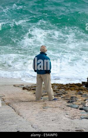 Ein senior woman Blick auf eine aufgewühlte Meer St Ives Cornwall England uk Stockfoto