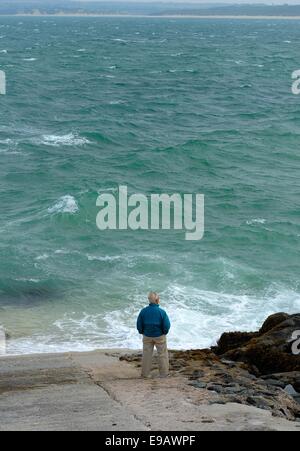 Ein senior woman Blick auf eine aufgewühlte Meer St Ives Cornwall England uk Stockfoto