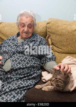 Ältere Frau streichelte ihre Katze im Haus. Stockfoto