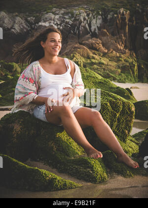 Schwangere Frau lächelnd am Strand im freien Stockfoto