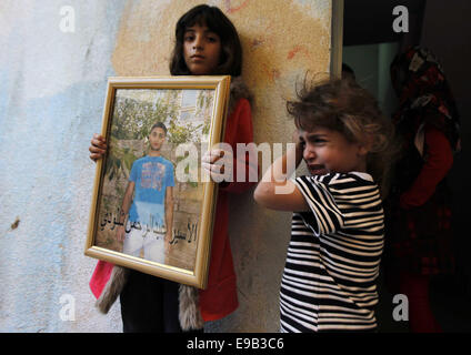 Jerusalem. 23. Oktober 2014. Die Schwester des palästinensischen Abdelrahman Shaludi, wer hat ein Baby getötet und sechs weitere in Jerusalem, nachdem er sein Fahrzeug Fußgänger in der Nähe von einer Straßenbahn in welche israelische Polizei genannt '' Fahrerflucht Terrorangriff rammte '' verletzt, schaut zu, wie ihre Schwester sein Porträt auf ihre Familie zu Hause in der Ost-Jerusalem-Nachbarschaft von Silwan hält. Shaludi starb an seinen Verletzungen, nachdem er erschossen wurde und von der Polizei verletzt, als er versuchte, die Szene zu spät am Abend vorher fliehen © Muammar Awad/APA Bilder/ZUMA Draht/Alamy Live News Stockfoto