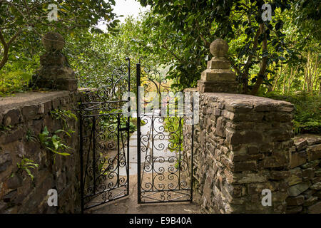 Ein paar von schmiedeeisernen Toren, führt in einen typischen englischen, gepflegten Garten. Stockfoto