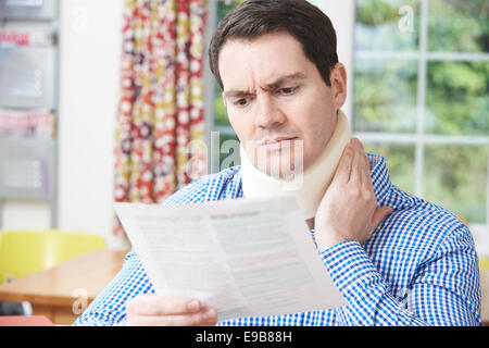 Mann liest Brief nach Erhalt Nackenverletzung Stockfoto