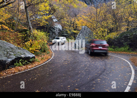 Auf kurvenreichen Highway 108 vorbeifahrende Autos passieren Felsbrocken im Schmuggler Notch State Park in der Nähe von Stowe Vermont USA mit Herbst Baum Laub Stockfoto