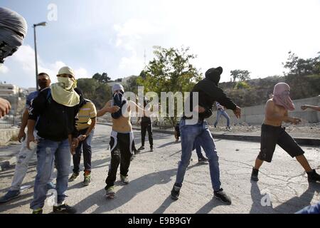 Jerusalem, Palästina. 23. Oktober 2014. Palästinensische Jugendliche Steinwurf gegen israelische Polizei bei Zusammenstößen im Stadtteil East Jerusalem von Issawija 23. Oktober 2014. Spannung in Jerusalem stieg am Mittwoch nach eine israelischen Baby starb und acht weitere Menschen verletzt, wurden wenn ein palästinensischer Mann sein Auto in Fußgänger an einer Jerusalem-Stadtbahn-Haltestelle schlug. Polizei erschossen den Fahrer flüchtete. Ein Krankenhaus-Beamter sagte der Fahrer starb später an seinen Verletzungen Credit: Muammar Awad/APA Bilder/ZUMA Draht/Alamy Live News Stockfoto