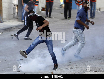 Jerusalem, Palästina. 23. Oktober 2014. Eine palästinensische Jugend tritt zurück ein Tränengas-Behälter bei Zusammenstößen mit der israelischen Polizei im Stadtteil East Jerusalem von Issawija 23. Oktober 2014. Spannung in Jerusalem stieg am Mittwoch nach eine israelischen Baby starb und acht weitere Menschen verletzt, wurden wenn ein palästinensischer Mann sein Auto in Fußgänger an einer Jerusalem-Stadtbahn-Haltestelle schlug. Polizei erschossen den Fahrer flüchtete. Ein Krankenhaus-Beamter sagte der Fahrer starb später an seinen Verletzungen Credit: Muammar Awad/APA Bilder/ZUMA Draht/Alamy Live News Stockfoto