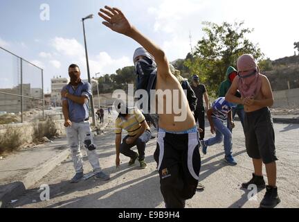 Jerusalem, Palästina. 23. Oktober 2014. Palästinensische Jugendliche Steinwurf gegen israelische Polizei bei Zusammenstößen im Stadtteil East Jerusalem von Issawija 23. Oktober 2014. Spannung in Jerusalem stieg am Mittwoch nach eine israelischen Baby starb und acht weitere Menschen verletzt, wurden wenn ein palästinensischer Mann sein Auto in Fußgänger an einer Jerusalem-Stadtbahn-Haltestelle schlug. Polizei erschossen den Fahrer flüchtete. Ein Krankenhaus-Beamter sagte der Fahrer starb später an seinen Verletzungen Credit: Muammar Awad/APA Bilder/ZUMA Draht/Alamy Live News Stockfoto