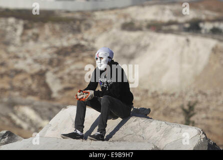 Jerusalem, Palästina. 23. Oktober 2014. Eine maskierte palästinensische Jugend blickt auf bei Zusammenstößen mit der israelischen Polizei im Stadtteil East Jerusalem von Issawija 23. Oktober 2014. Spannung in Jerusalem stieg am Mittwoch nach eine israelischen Baby starb und acht weitere Menschen verletzt, wurden wenn ein palästinensischer Mann sein Auto in Fußgänger an einer Jerusalem-Stadtbahn-Haltestelle schlug. Polizei erschossen den Fahrer flüchtete. Ein Krankenhaus-Beamter sagte der Fahrer starb später an seinen Verletzungen Credit: Muammar Awad/APA Bilder/ZUMA Draht/Alamy Live News Stockfoto