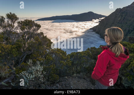 Junge Frau mit Blick auf ein Meer von Wolken über Cilaos Becken, Cirque de Cilaos, Reunion, Afrika Stockfoto