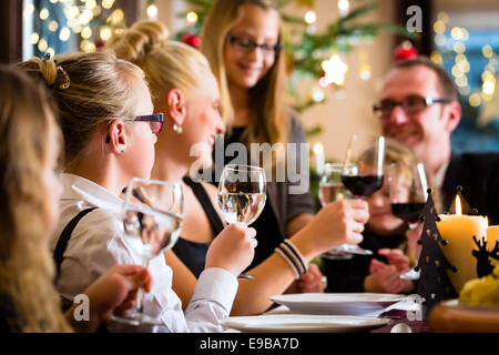 Deutsche Eltern und Kinder Toasten mit Wein und Wasser am Weihnachtsessen Stockfoto