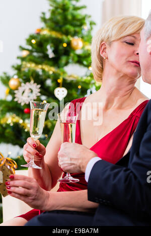 Ältere Mann und Frau feiern Heiligabend mit Kuss und Sekt Stockfoto