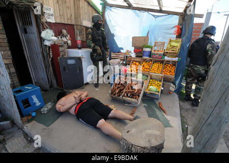 Buenos Aires, Argentinien. 23. Oktober 2014. Polizisten bewachen einen Häftling während einer Anti-Drogen-Operation im Los Paraguayos Village in der Nähe von Quilmes-Stadt im Bundesstaat Buenos Aires, Argentinien, auf 23. Oktober 2014. Polizisten verhaftet fünf Personen und Dosen von Kokain und Marihuana während der Operation, nach lokalen Presse beschlagnahmt. Bildnachweis: TELAM/Xinhua/Alamy Live-Nachrichten Stockfoto