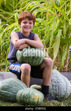 Porträt eines jungen Mannes hält einen großen Kürbis in einem Hinterhof-Garten Stockfoto