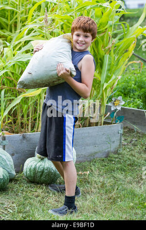 Porträt eines jungen Mannes mit einer großen Tasche von Mulch für den Garten Hochbeeten Stockfoto