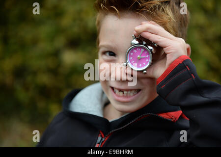 Friedrichshafen, Deutschland. 23. Oktober 2014. Grundschule Schüler Vincent hält einen Wecker vor seinem Gesicht in Friedrichshafen, Deutschland, 23. Oktober 2014. Uhren werden auf Winterzeit am 26. Oktober 2014 um eine Stunde zurückgedreht werden. Foto: Felix Kaestle/Dpa/Alamy Live News Stockfoto