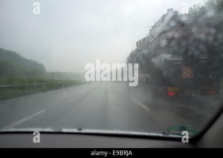 Übergabe eines LKWs Transport von verschrotteten Autos bei starkem Regen auf der Autobahn A9 südlich von München, Bayern, Deutschland. Stockfoto