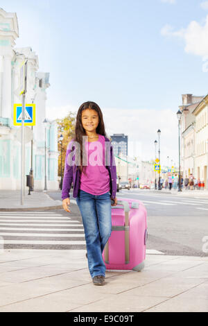 Kleine Asiatin hält Rosa Gepäck auf Straße Stockfoto