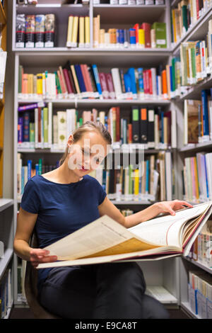 Hübsche, junge Frau, die ein altes Buch in Archiven zu studieren Stockfoto