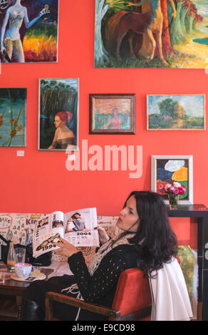 Frau liest Magazin in einer Bar. Gemälde an der Wand Stockfoto