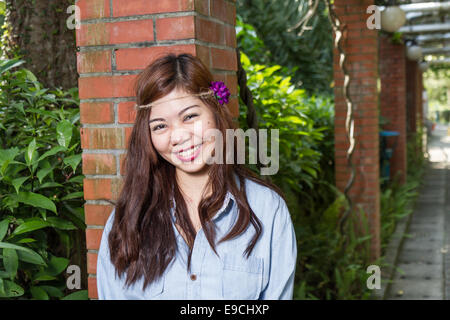 Pinoy Frau in einem grünen Garten auf Hof, gemauerte Säule gelehnt Stockfoto