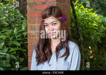 Pinoy Frau in einem grünen Garten auf Hof, gemauerte Säule gelehnt Stockfoto