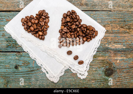 Zwei Herzen aus Kaffeebohnen auf hölzernen Hintergrund gemacht. Aus einer Reihe Kaffee Zeit Stockfoto