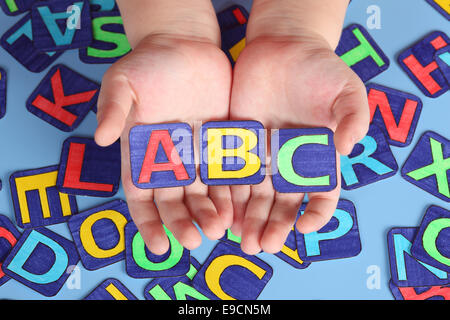 "ABC" in die Hände des Kindes mit Buchstaben auf blauem Hintergrund. Briefe von mir gezeichnet. Stockfoto