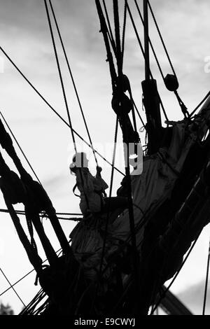 Junge Frau Klettern in der Takelage eines großen Schiffes. Stockfoto