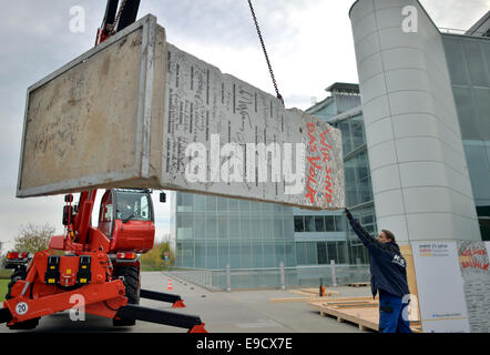 Leipzig, Deutschland. 25. Oktober 2014. Ein Kran hebt Sie ein Segment der Berliner Mauer in Leipzig, Deutschland, 25. Oktober 2014. Das Erdgas-Unternehmen Verbundnetz Gas AG (VNG) Versand sein Stück von der Wand, das im Jahr 2009 gekauft wurde, nach Washington. Es wird auf dem Gelände der deutschen Botschaft im Rahmen einer Feierstunde am 13. November 2014 übergeben. Das Stück wurde von einem Leipziger Künstler gemalt und trägt Biserujka von verschiedenen Persönlichkeiten wie der ehemalige Bundeskanzler Kohl und ehemaligen uns Secretarie der staatlichen Kissigner und Baker. Foto: Hendrik Schmidt/Dpa/Alamy Live News Stockfoto