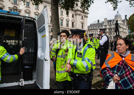 London, UK. 25. Oktober 2014. Bild: Verhaftet wegen angeblich brechen seiner Kautionsbedingungen nicht ist einen jungen Mann zurück zur "Green", die zuvor für ein 28 Stunden Sit-in auf dem Sockel der Churchills Statue, verhaftet worden war von Polizisten abgeführt. Aktivisten besetzen Demokratie weiter ihren kleinen Protest gegen "den Kapitalismus der Demokratie, außerhalb des Parlaments Usurpation". Sie fordern, dass die Regierung "Menschen vor dem Profit" setzt und das vorgeschlagene TTIP Protokoll zwischen Europa und den USA fallen gelassen wird. Bildnachweis: Paul Davey/Alamy Live-Nachrichten Stockfoto