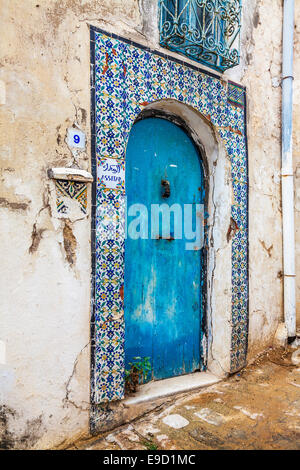 Eine alte, blaue Eingangstür, umgeben von traditionellen keramischen Fliesen in Sidi Bou Said, Tunesien. Stockfoto