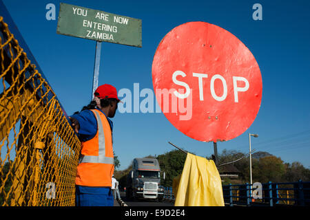 Eine Frau steuert den Datenverkehr zwischen Sambia und Simbabwe.  Ein STOP-Schild zeigt, dass wir Sambia eintreten. Heute eines der V Stockfoto