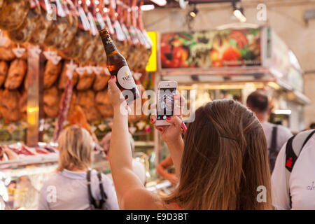 Frau fotografieren Bierflasche mit ihrem Iphone auf dem zentralen Markt, Valencia, Spanien. Bier nach dem Fluss Turia Stockfoto