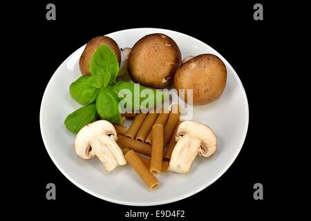 Baby Bella Pilze, Pasta und Basilikum auf einem schwarzen Hintergrund. Stockfoto