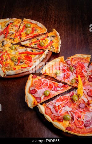 Pizza mit Salami, Peppeeoni, Oliven, Tomaten und gelbe Paprika Stockfoto