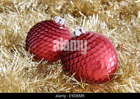 Zwei rote Pailletten Weihnachtskugeln auf goldenen Lametta. Stockfoto