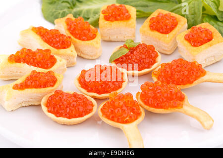 Roter Kaviar in Gebäck und Salat auf Teller. Stockfoto