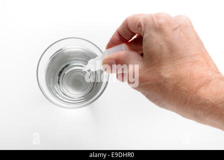 Die Hand des Menschen setzen Apotheke Tropfen in ein Glas transparent Wasser auf weißem Hintergrund Stockfoto