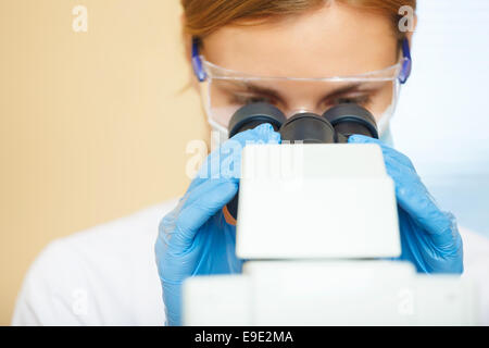 Schöne Frau in einem Labor arbeiten mit einem Mikroskop. Stockfoto