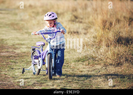 Kleine lustige Kind Reiten Fahrrad mit Stützrädern. Stockfoto