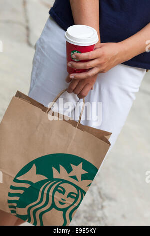 Paphos, Zypern - 23. November 2013 Frau stehen auf der Straße mit Starbucks zum Mitnehmen Papier Tasche und Urlaub Pappbecher Kaffee Stockfoto