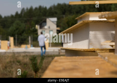 Nahaufnahme Detail eines isolierten Wand-Panels liegen auf einer Baustelle mit den Arbeitnehmern beschäftigt, die auf Kosten des Hauses in der backgr Stockfoto