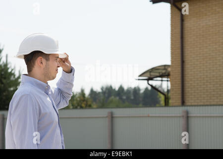 Junge Männchen Bauingenieur mit weißen Kopf Protector Besuch der Website zu erstellen-Updates zu überwachen. Stockfoto