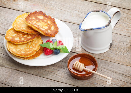 Pfannkuchen mit Himbeeren, Heidelbeeren, Milch und Honig Sirup. Auf Holztisch Stockfoto